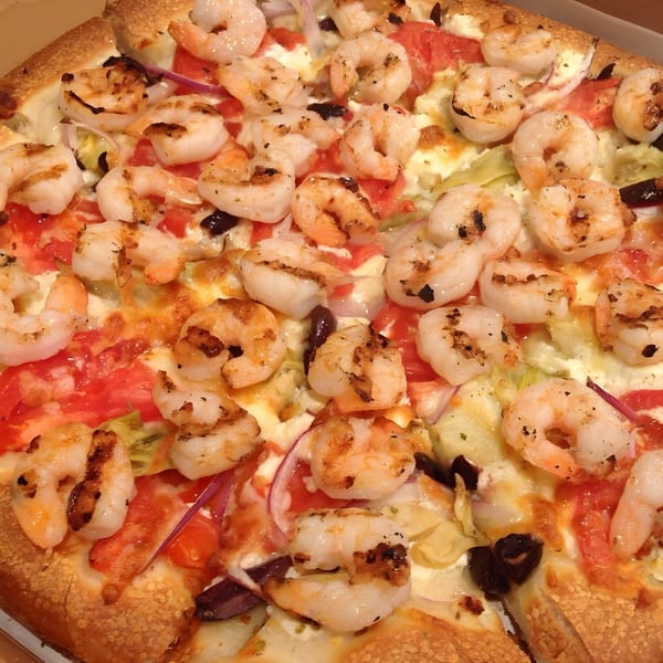 Close-up of a Townies Feel Good Food pizza topped with grilled shrimp, tomatoes, and red onions.